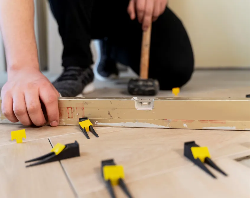 Flooring installer leveling new planks with spacers and a rubber mallet in Tampa, FL